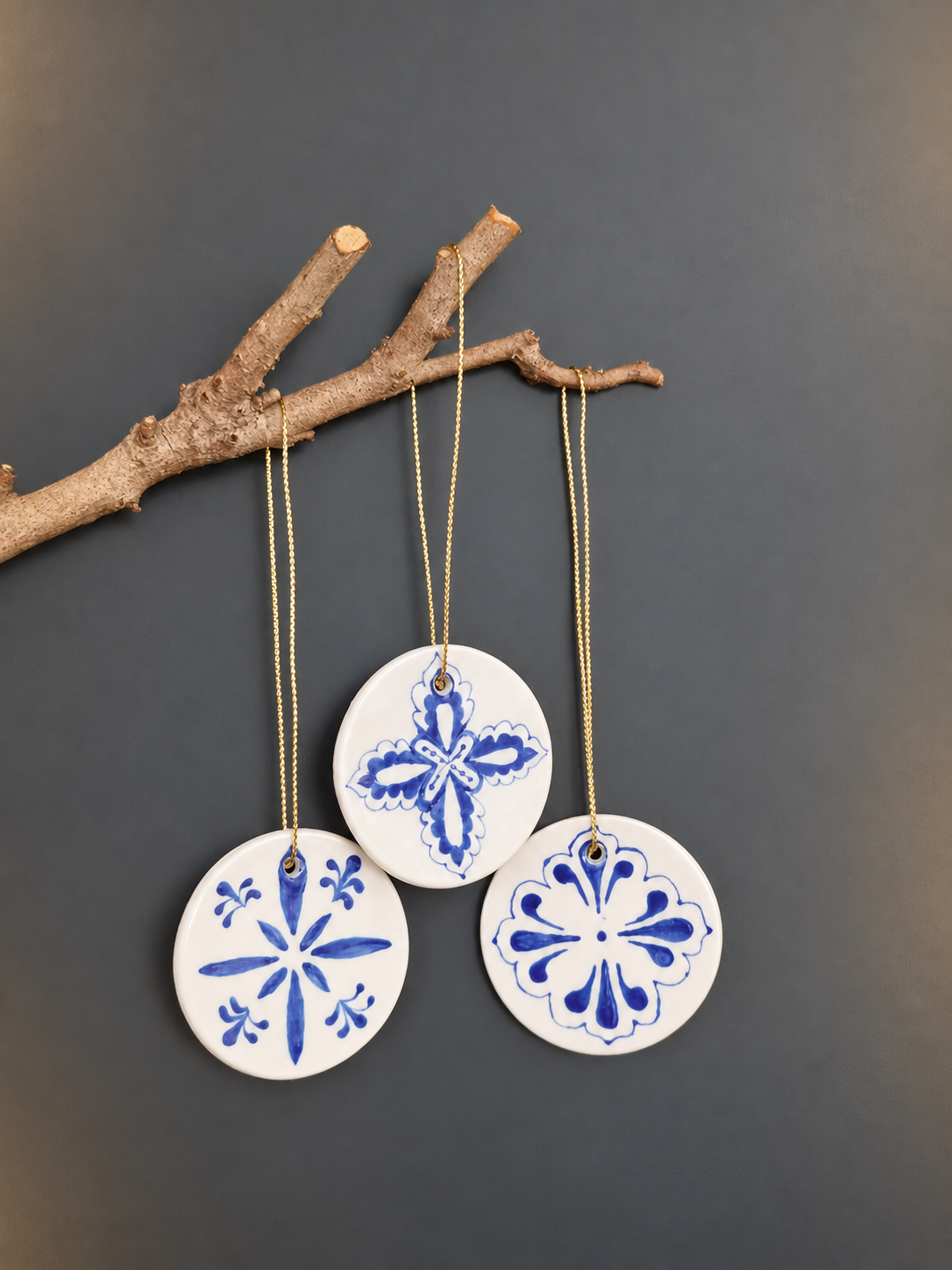 Three blue and white hand-painted ceramic disc ornaments hanging from branch alternative view